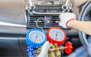 Mechanic checking car air conditioning system with pressure gauges inside a vehicle