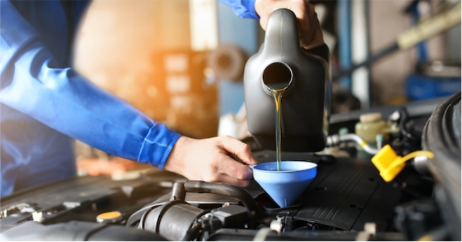 mechanic pouring engine oil into a car engine, demonstrating an engine oil change