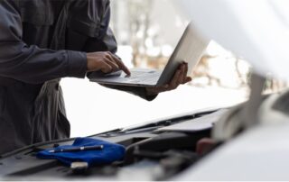 Mechanic using laptop during car servicing regular maintenance saves long-term costs