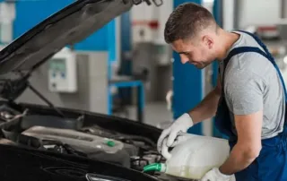 Mechanic pouring fresh oil into a car engine.